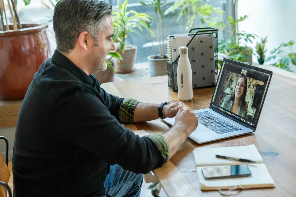 Man in a 1-on-1 video consultation on his laptop at a home desk