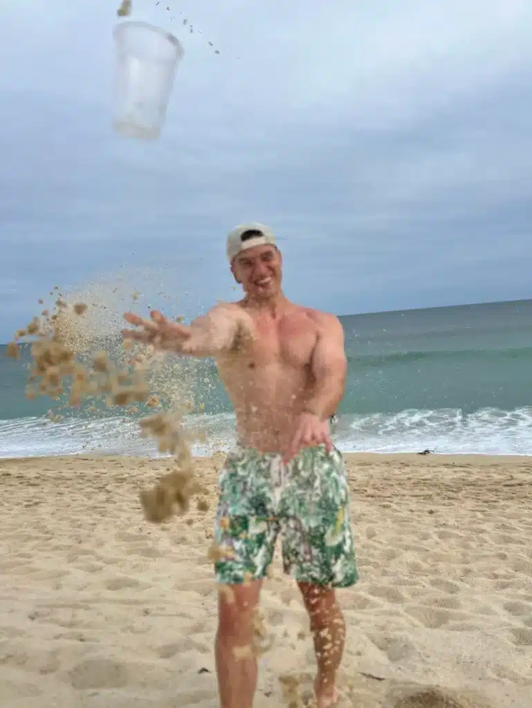 James throwing a cup of sand on a beach in Los Cabos, Mexico